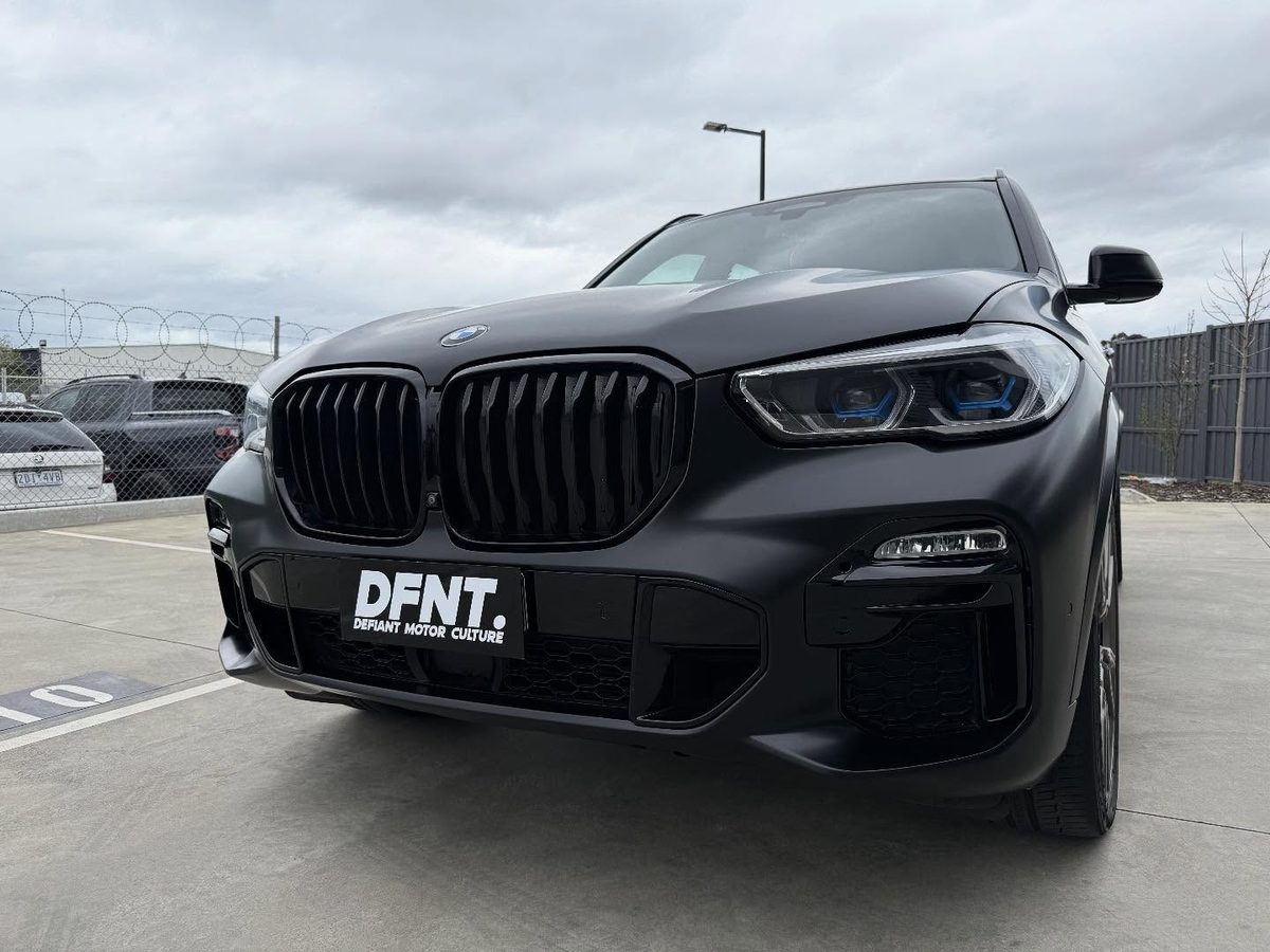 A BMW X5 in a satin black wrap with the grille finished in gloss black