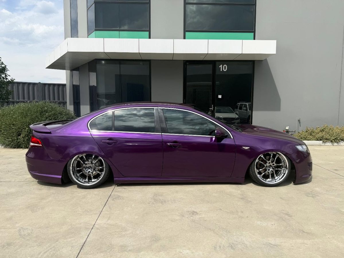 A Ford Falcon in a purple colour change wrap, lowered, with tinted windows