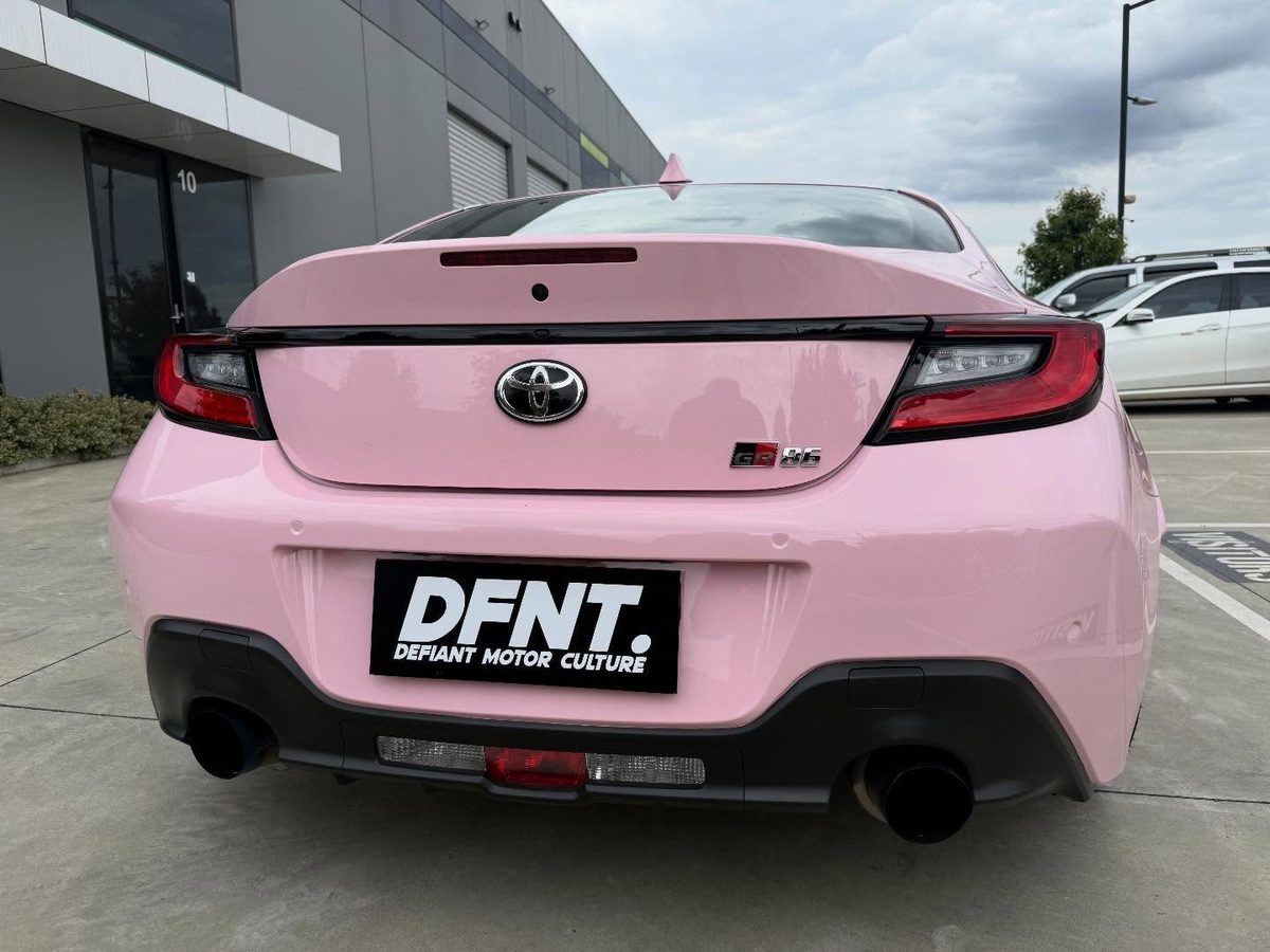 The rear of a Toyota GR86 in a gloss pink colour change wrap