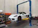 A white Porsche 718 up on the hoist
