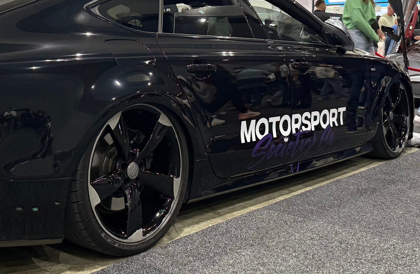 Vinyl signage cut and laid along the door of a black Audi RS7